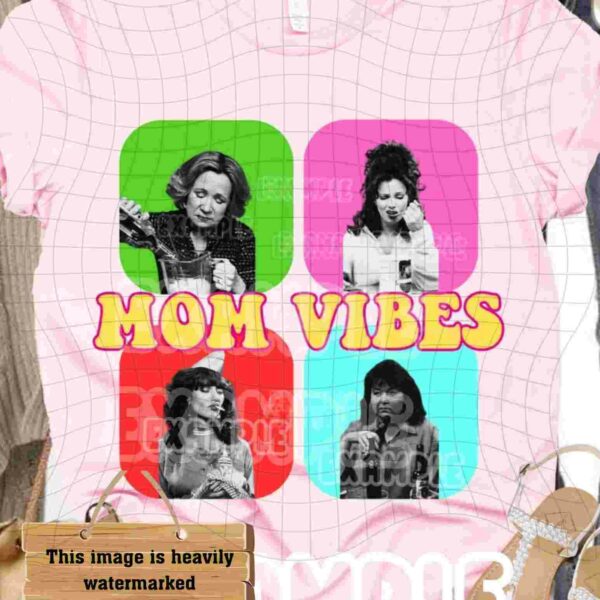 A pink T-shirt is displayed with colorful panels showing four black-and-white images of women. The text "MOM VIBES" is prominently featured in yellow with a red outline. The background includes various accessories, such as shoes and a bag.