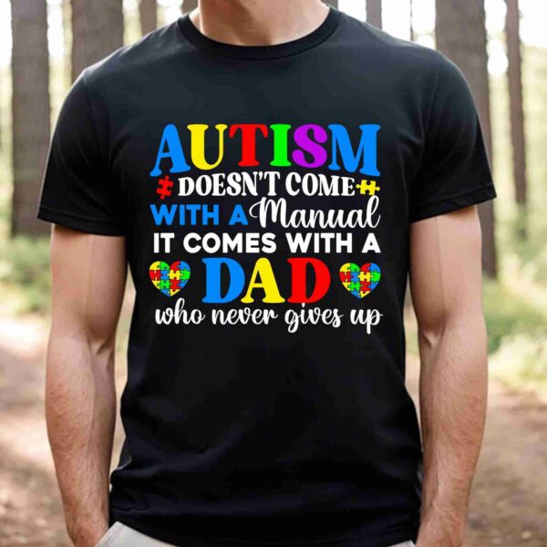 A person wearing a black T-shirt that reads, "Autism doesn't come with a manual, it comes with a dad who never gives up," with colorful text and heart designs.