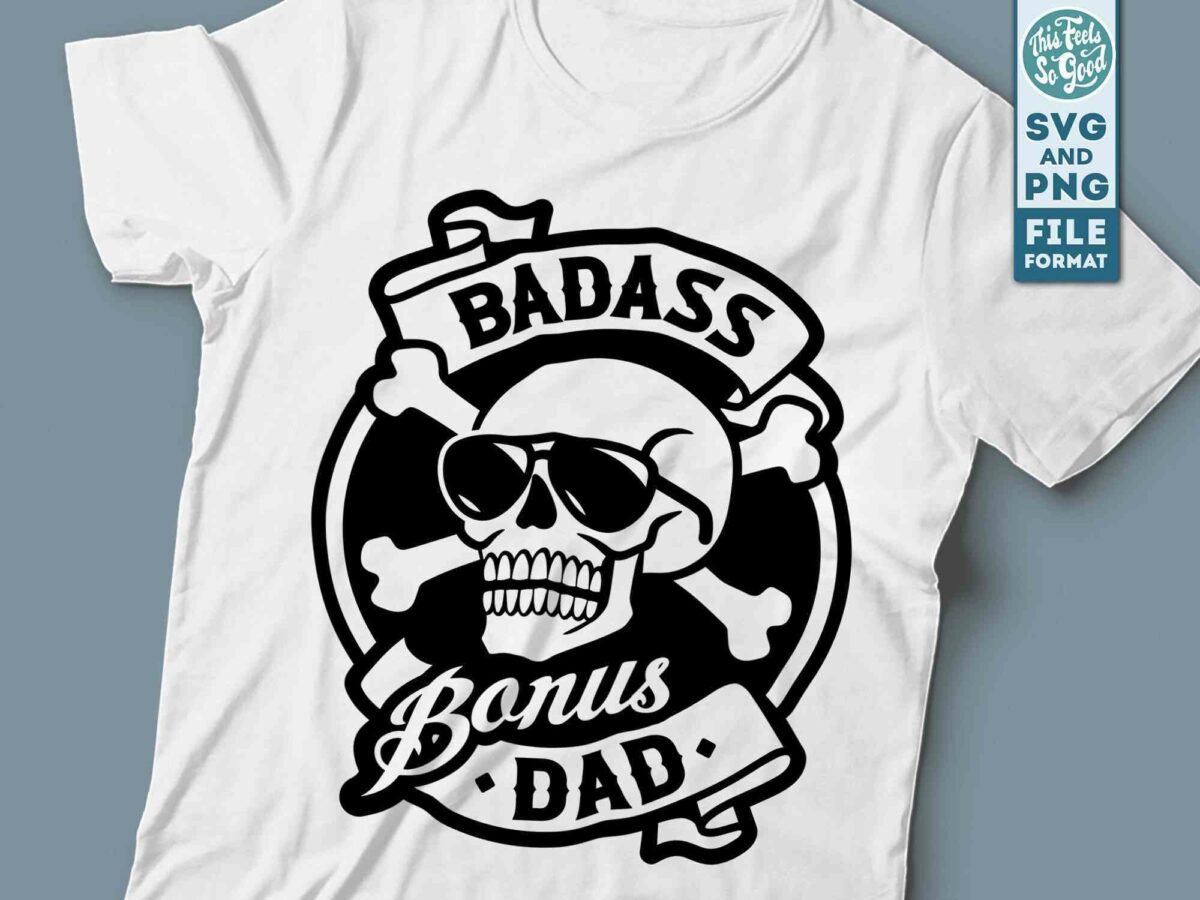 A white t-shirt featuring a black graphic of a skull wearing sunglasses and two crossed bones behind it. The design includes the text "BADASS Bonus DAD" arranged in a banner style above and below the skull. A sticker on the shirt indicates SVG and PNG file format.
