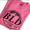 Pink T-shirt with "BLD Bang Local Dads" written in black text featuring a leopard print mountain graphic above the letters.