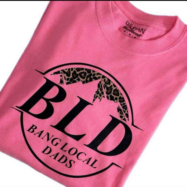 Pink T-shirt with "BLD Bang Local Dads" written in black text featuring a leopard print mountain graphic above the letters.
