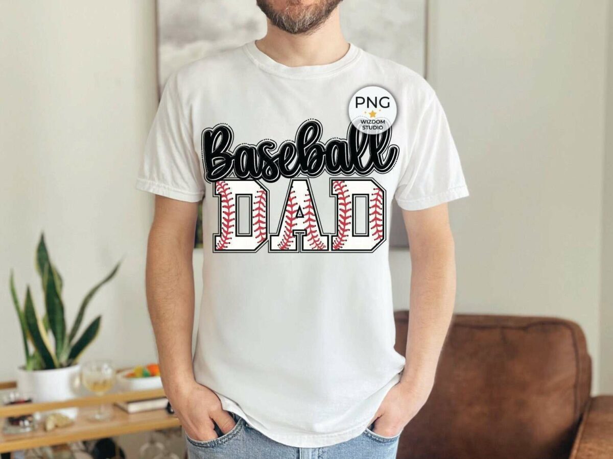 A person wearing a white t-shirt that reads "Baseball Dad" stands indoors. In the background, there's a plant on a table and a brown chair.