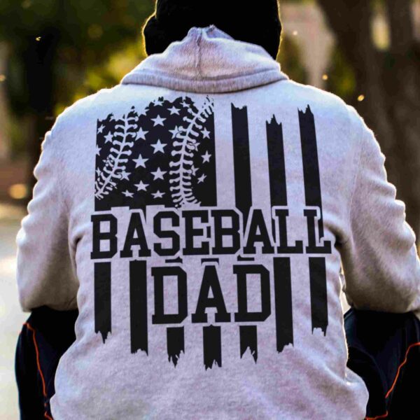 Person wearing a hoodie with an American flag and a baseball design, along with the text "BASEBALL DAD" on the back.