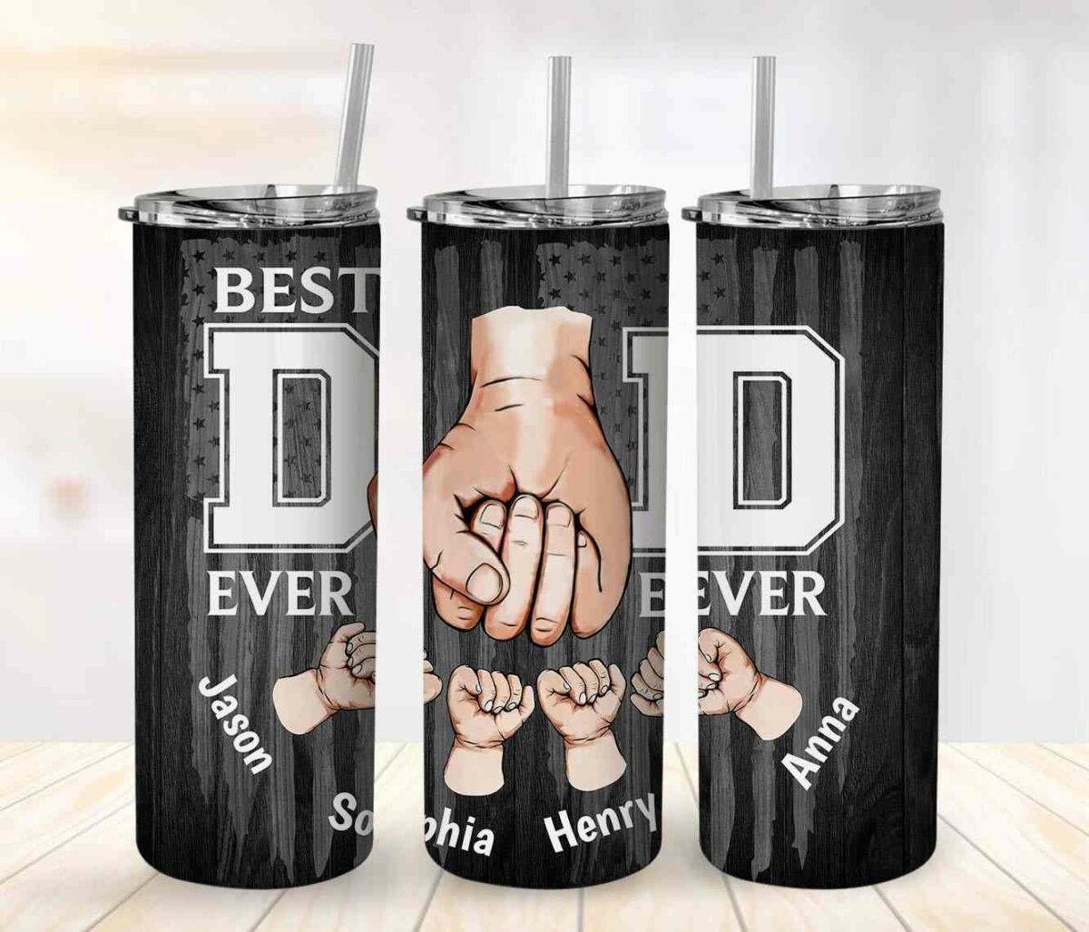 Three tall drink tumblers with straws, featuring "Best Dad Ever" text and images of a large hand fist-bumping smaller hands named Jason, Sophia, Henry, and Anna, against a dark wood-like background.