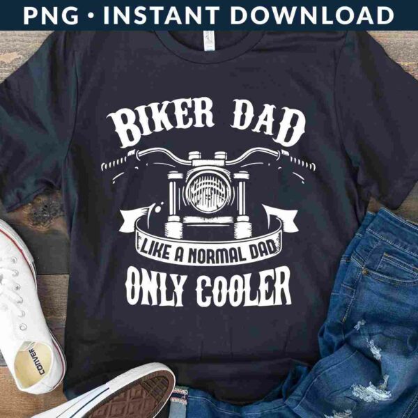 A black T-shirt with the text "Biker Dad Like a Normal Dad Only Cooler" featuring a motorcycle graphic. It's displayed with white sneakers and blue jeans on a wooden surface.