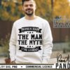 Alt Text: A man is wearing a white sweatshirt with the text "BONUS DAD, THE MAN, THE MYTH, THE LEGEND" in bold, black font. The background features an outdoor setting with greenery.