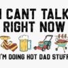 Text reads "I CAN'T TALK RIGHT NOW I'M DOING HOT DAD STUFF" above illustrations of a tie, a mug of beer, a lawnmower, and a grill with sausages.