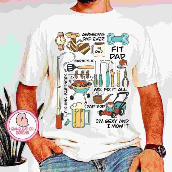 A person wearing a white t-shirt with colorful illustrations and text representing various dad-related themes. The shirt features items like tools, a fishing rod, a grill, a lawnmower, and phrases such as "Awesome Dad Ever," "#1 Dad," "Fit Dad," "Barbecue," and "Fishing Partner.