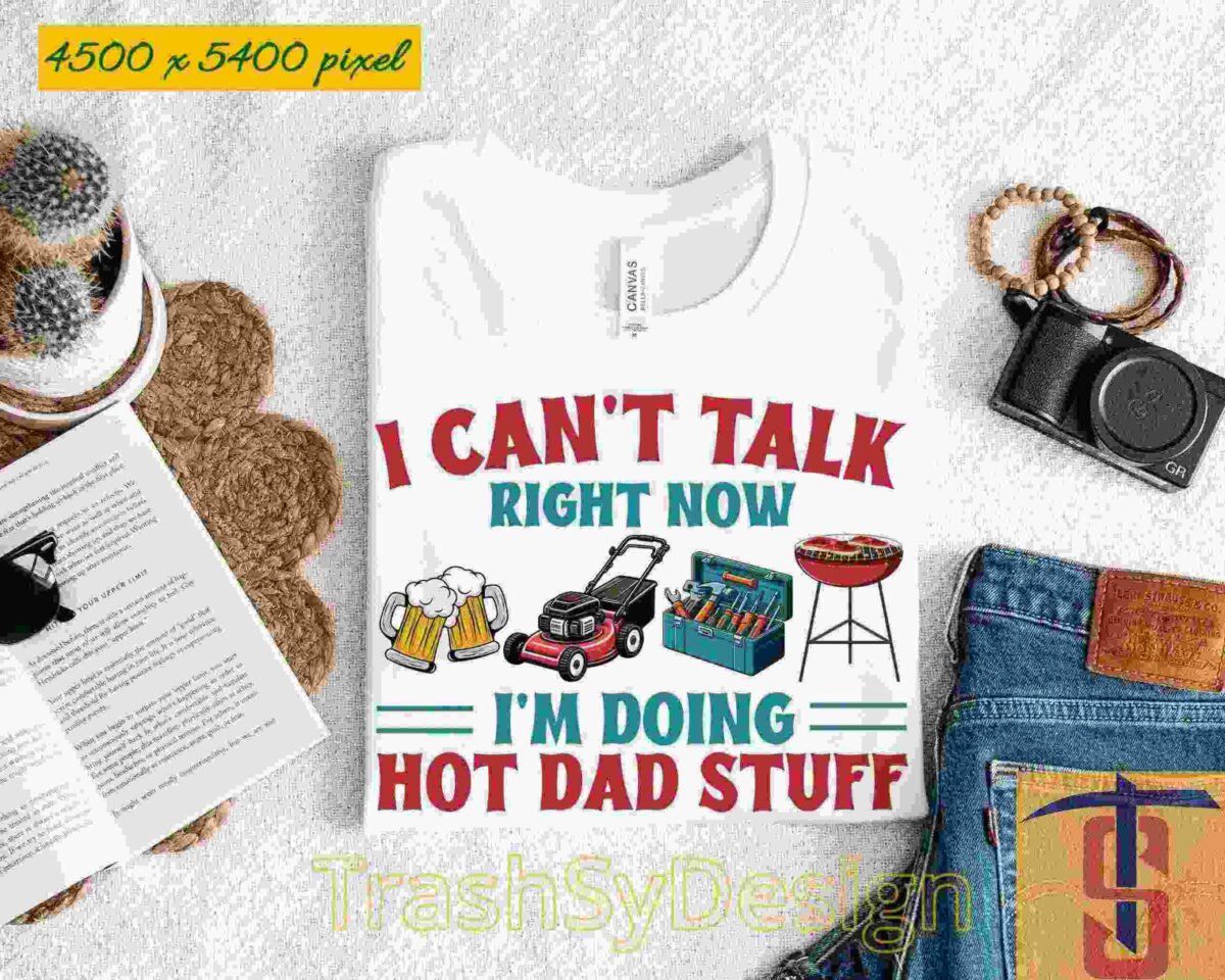 Alt Text: White T-shirt with text: "I CAN'T TALK RIGHT NOW I'M DOING HOT DAD STUFF" alongside images of a beer, grill, and lawnmower. Laid out with jeans, a camera, a book, and sunglasses.