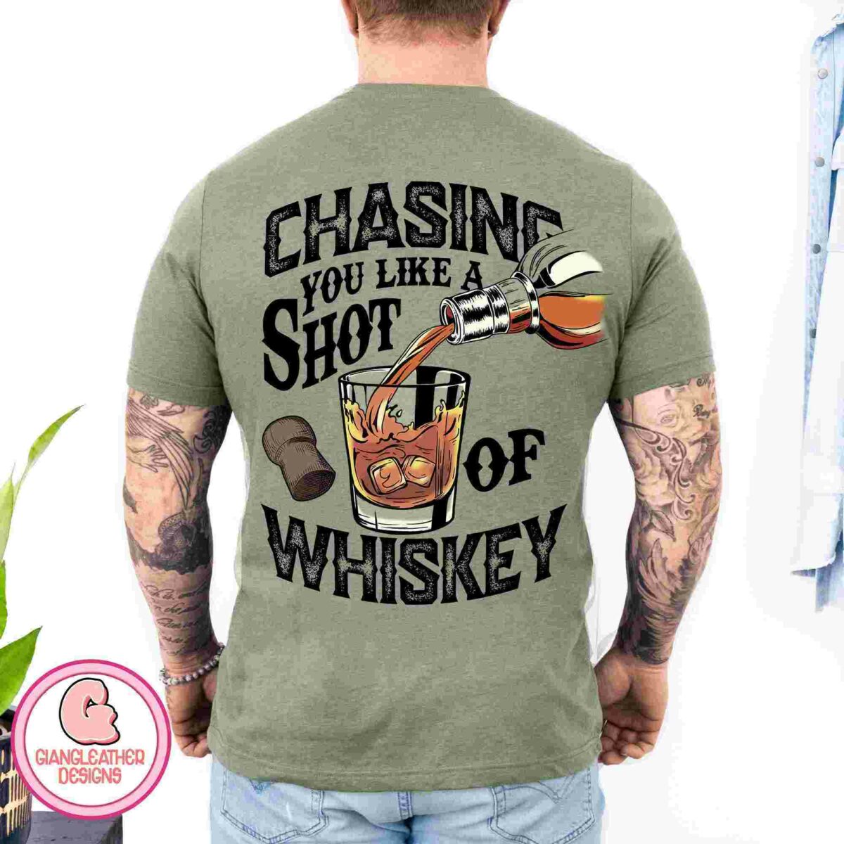 Alt Text: Man wearing a green t-shirt with the text "Chasing you like a shot of whiskey" and an illustration of a whiskey bottle pouring into a glass.