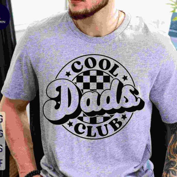 Man wearing a grey t-shirt with a "Cool Dads Club" logo featuring a checkered pattern in the background.