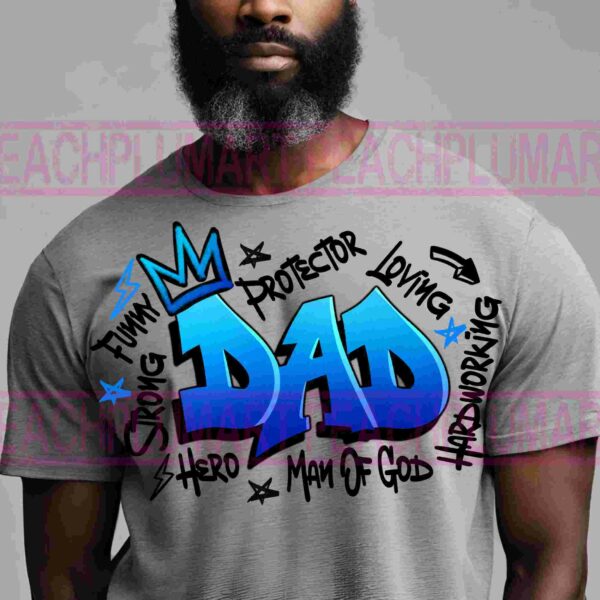 A man with a dark beard wears a gray T-shirt with colorful, graffiti-style text that reads "DAD" in large blue letters. Surrounding words include "Protector," "Loving," "Hardworking," "Funny," "Strong," "Hero," and "Man of God.