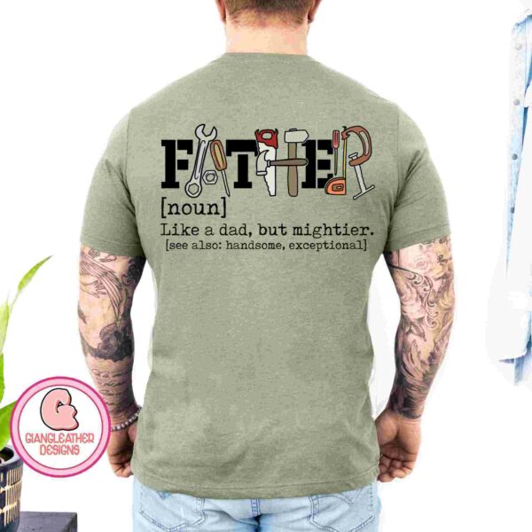 A man with tattooed arms wears a light green T-shirt. The back of his shirt displays the word "FATHER" with each letter illustrated by a tool. Below, it reads: "[noun] Like a dad, but mightier. [see also: handsome, exceptional]". The shirt design is by Giancleather Designs.