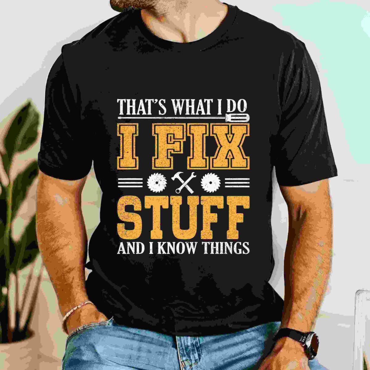 A person wearing a black T-shirt with the text "That's what I do. I fix stuff and I know things" printed on it in yellow and white letters, featuring gear and wrench graphics.