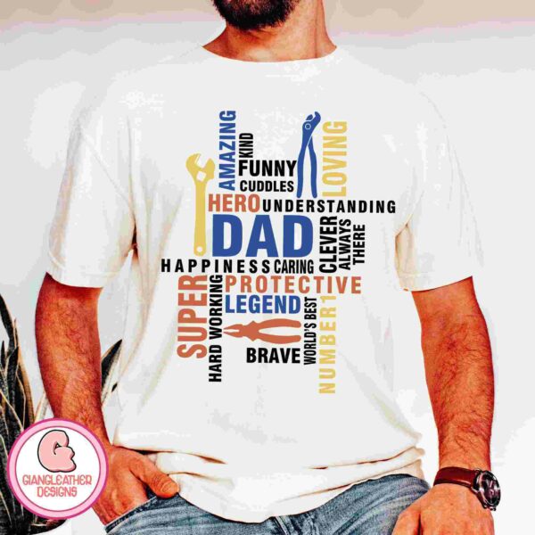 A man wears a white T-shirt featuring a colorful word art design around the word "DAD" in the center. Words like "HERO," "AMAZING," "LOVING," "FUNNY," and "PROTECTIVE" surround it. The design includes images of tools. The shirt displays a logo for GIANLeather Designs.