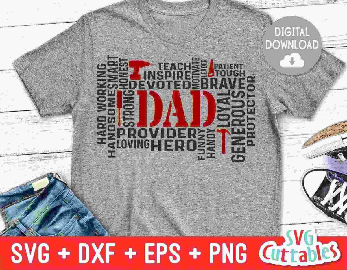 Gray T-shirt with the word "Dad" in large red letters surrounded by words like hero, strong, supportive, brave, loyal, teacher, and provider in black and red. The words form a rectangular shape. Near the T-shirt are a pair of black and white sneakers and folded jeans.