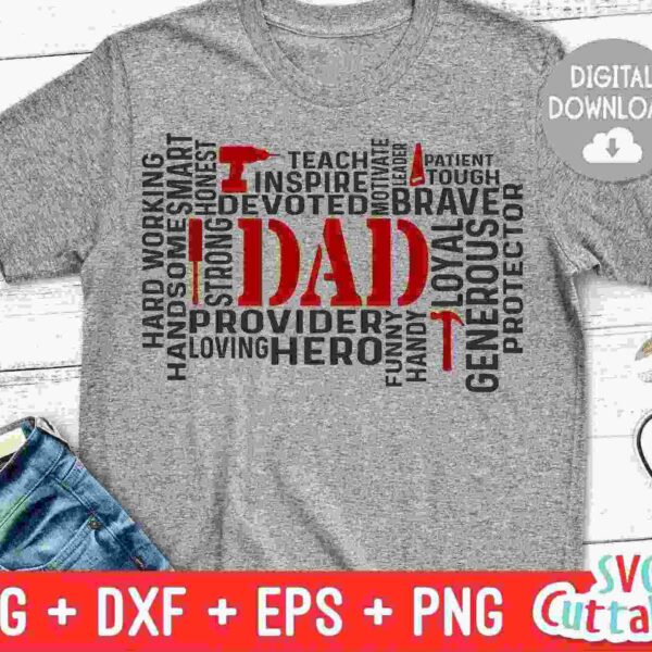 Gray T-shirt with the word "Dad" in large red letters surrounded by words like hero, strong, supportive, brave, loyal, teacher, and provider in black and red. The words form a rectangular shape. Near the T-shirt are a pair of black and white sneakers and folded jeans.