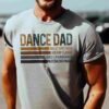 A person wearing a light gray T-shirt that reads "DANCE DAD" followed by "Ballet Spectacle, Holiday Classic, Dance Extravaganza, Nutcracker Magic" in smaller text below.