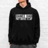 A person wearing a black hoodie with the text "DANCE DAD PAY· DRIVE· CLAP" printed on the front, standing in front of a white brick wall.