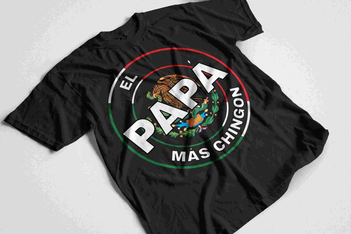 Black t-shirt with a circular logo featuring an eagle and cactus. Text reads "El Papá Más Chingón" in Spanish, meaning "The Coolest Dad." The logo's colors are green, white, and red.