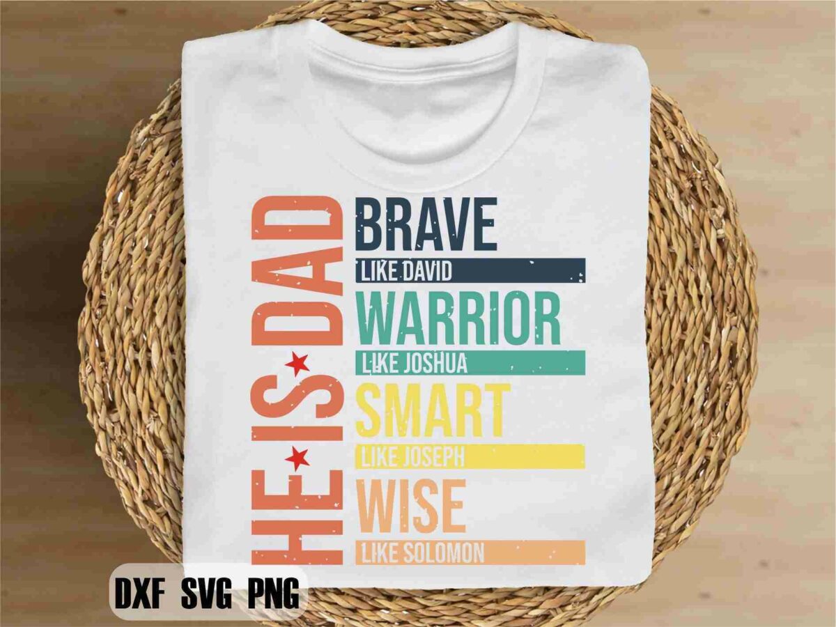 A white T-shirt is placed on a wicker basket. The design on the T-shirt reads "HE IS DAD" in vertical text, followed by "BRAVE like David", "WARRIOR like Joshua", "SMART like Joseph", and "WISE like Solomon" in horizontal text with colorful bars.