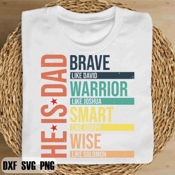 A white T-shirt is placed on a wicker basket. The design on the T-shirt reads "HE IS DAD" in vertical text, followed by "BRAVE like David", "WARRIOR like Joshua", "SMART like Joseph", and "WISE like Solomon" in horizontal text with colorful bars.