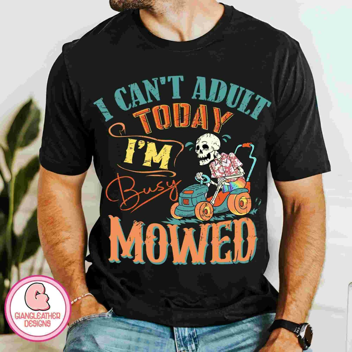 A person wearing a black T-shirt with colorful text that reads, "I can't adult today, I'm busy mowed," and a graphic of a skeleton driving a lawnmower.