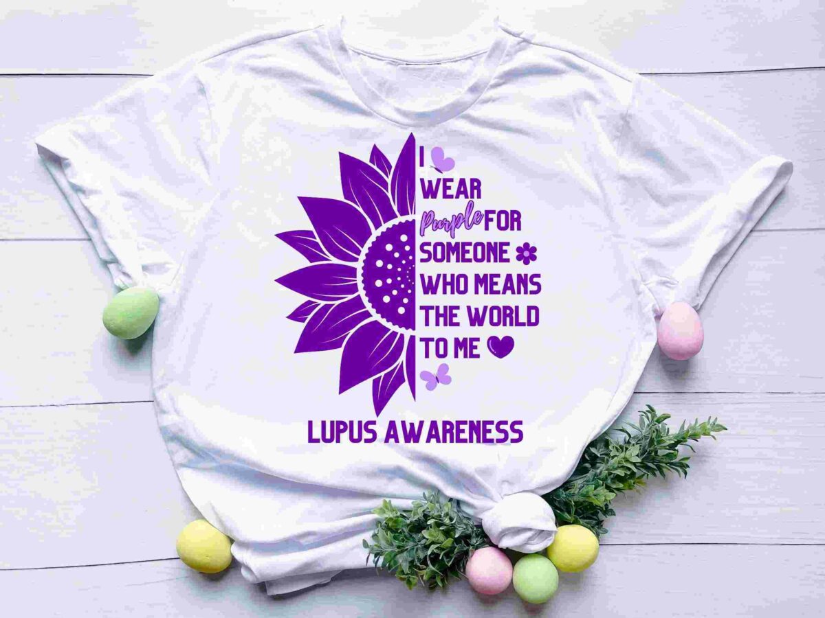White T-shirt with a purple sunflower graphic, text reading “I wear purple for someone who means the world to me,” and “Lupus Awareness.” Decorated with eggs and foliage.