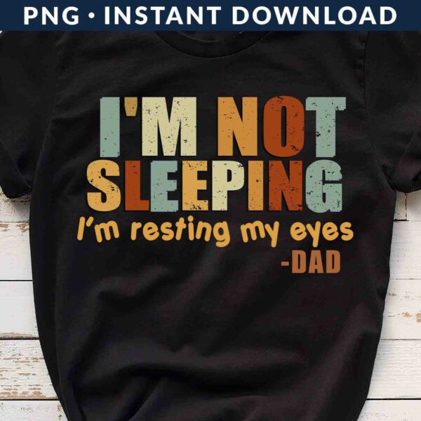 A black t-shirt with the text "I'M NOT SLEEPING, I'm resting my eyes -DAD" in bold, multicolored letters.