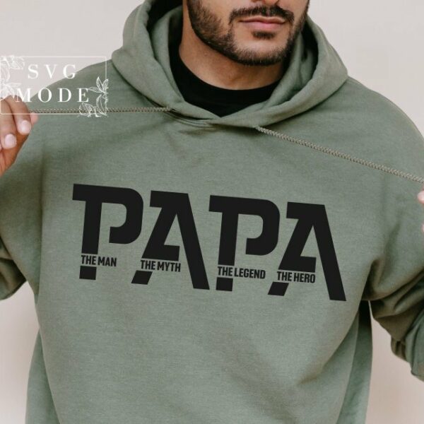 A person wearing a green hoodie with the word "PAPA" printed in large letters, followed by smaller text that reads "The Man, The Myth, The Legend, The Hero.