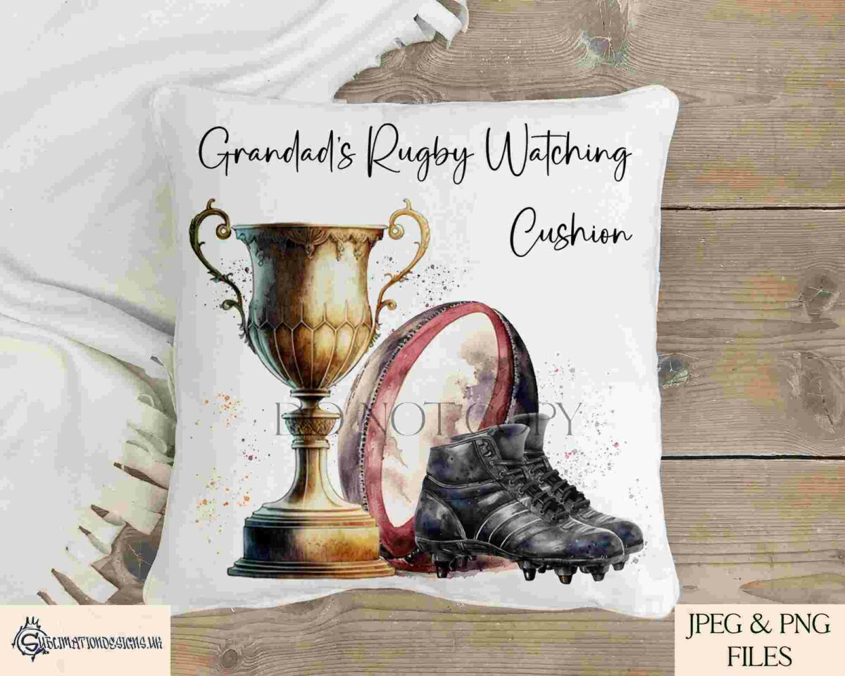 A throw pillow featuring a design with a trophy, a rugby ball, and cleats. Text reads "Grandad's Rugby Watching Cushion." The pillow is placed on a wooden surface with a white fabric in the background.