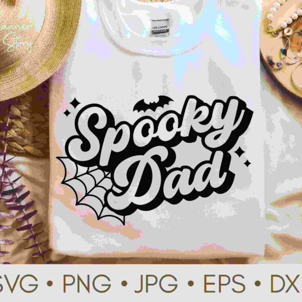 A white sweatshirt with a "Spooky Dad" design featuring a bat and spider web, displayed beside a straw hat and beads.