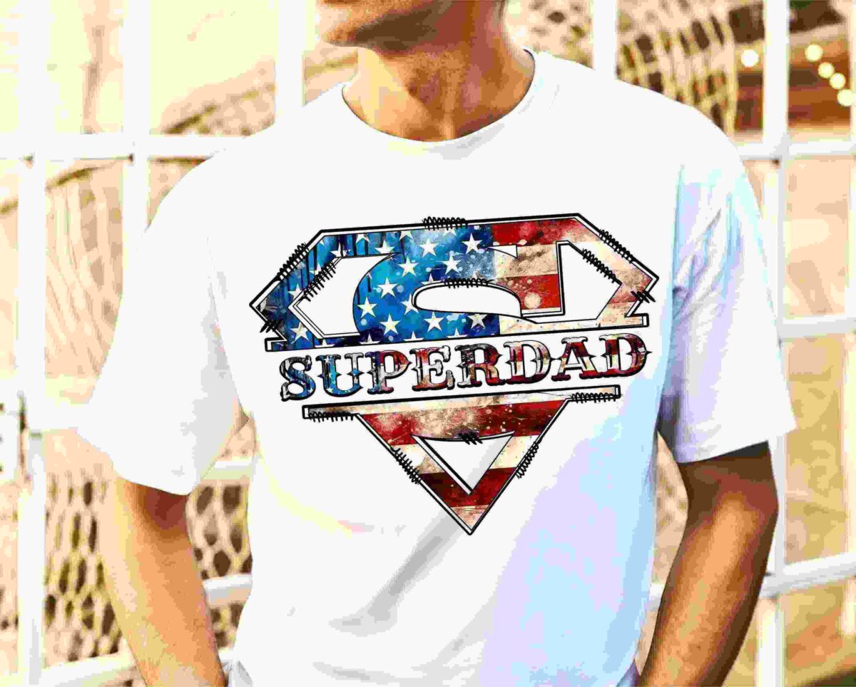 Man wearing a white t-shirt with an illustrated "Superdad" logo, designed in a style reminiscent of the Superman emblem, embellished with the American flag's stars and stripes.