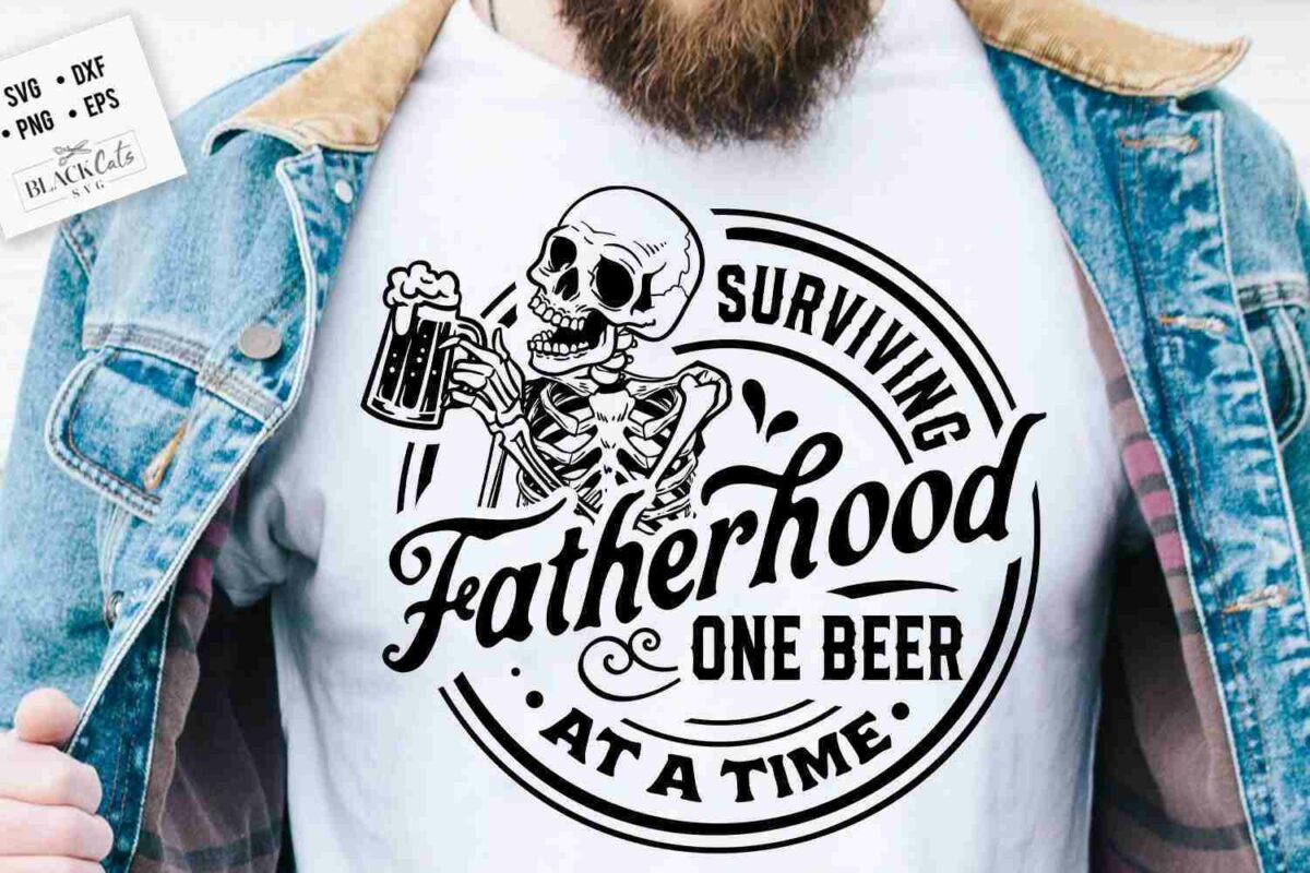 A person wearing a white t-shirt under a denim jacket. The t-shirt features a graphic of a skeleton holding a beer mug and reads "Surviving Fatherhood One Beer At a Time" in bold, stylized font.