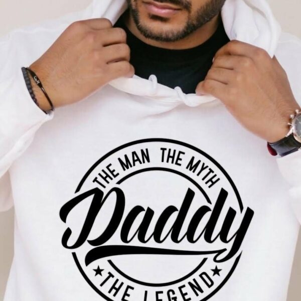 A person wearing a white hoodie with the words "The Man, The Myth, Daddy, The Legend" printed on the front. They are adjusting the hood with their hands.